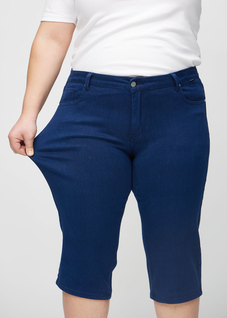 Plus size-modellen stretchar caprisen vid låret för att visa stretch.