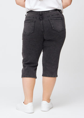 Mörkgrå denim regular capris sedd bakifrån på en plus-size-modell, så att man kan se hela produkten.