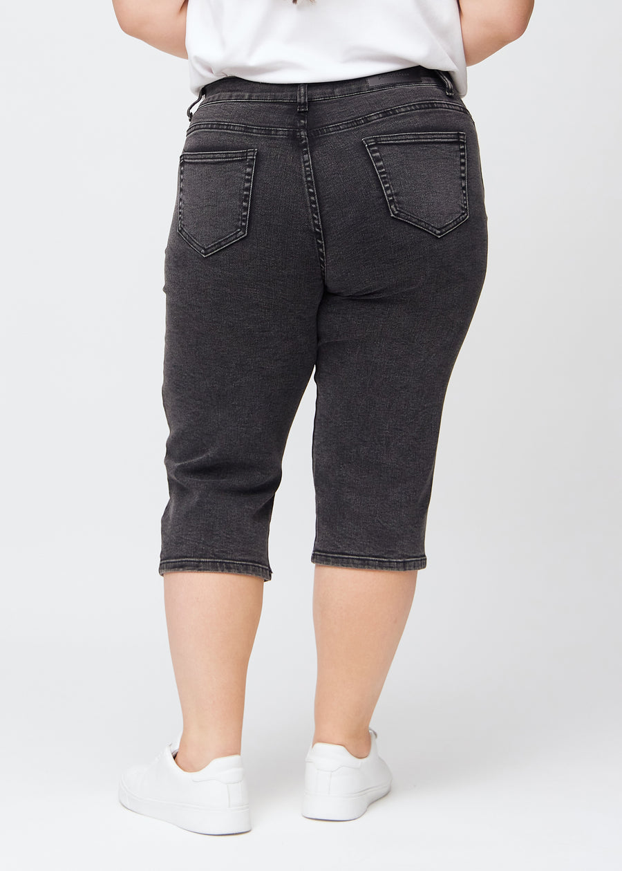 Mörkgrå denim regular capris sedd bakifrån på en plus-size-modell, så att man kan se hela produkten.