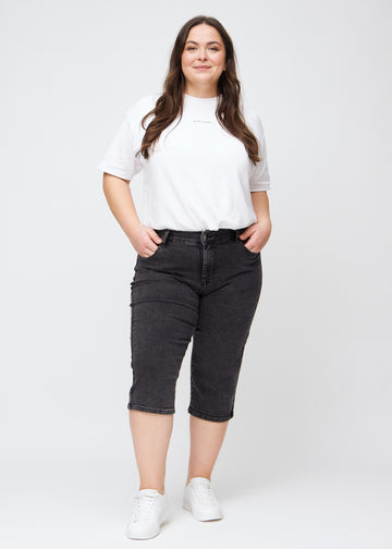 Helbild av en plus-size-modell i mörkgrå denim regular capris.