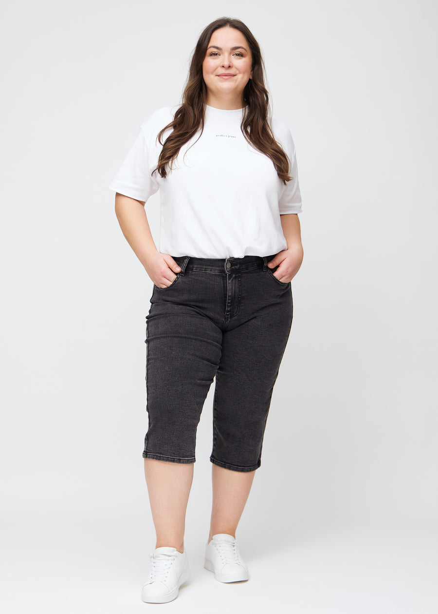 Helbild av en plus-size-modell i mörkgrå denim regular capris.