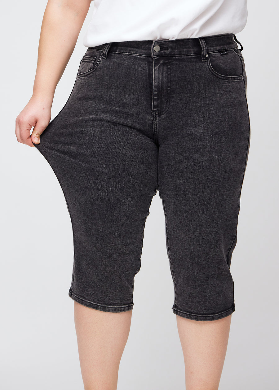 Plus-size-modellen sträcker caprisen vid låret för att visa stretch.