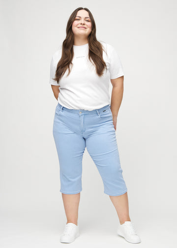 Helbild av en plus size-modell i ljusblå regular capris.