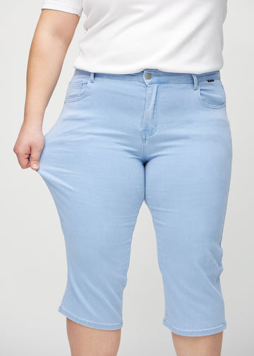 Plus size-modellen drar ut caprisen vid låret för att visa stretch.