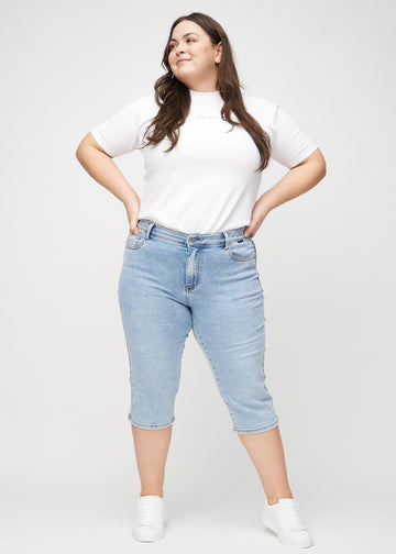 Helbild av en plus-size-modell i ljus denim regular capris.