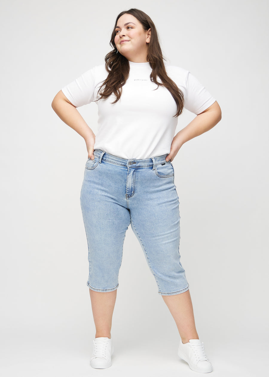 Helbild av en plus-size-modell i ljus denim regular capris.