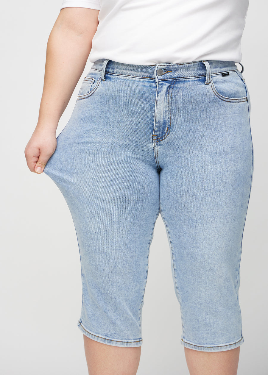 Plus-size-modellen drar ut caprisen vid låret för att visa stretchen.