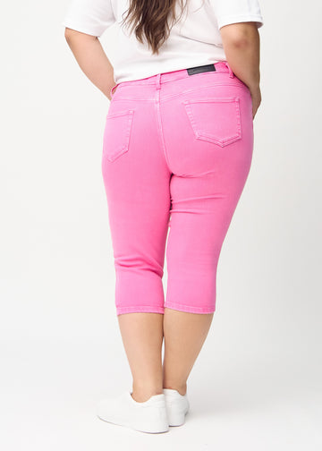 Skinnycapris för kvinnor i pastellrosa jeanstyg, färgen Flamingos. Bakifrån på en plus size-modell, med fokus på passform och bakfickor.