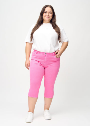 Skinnycapris för kvinnor i pastellrosa jeanstyg, färgen Flamingos. Helbild av en plus size-modell som bär capris.