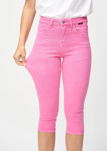 Skinnycapris för kvinnor i pastellrosa jeanstyg, färgen Flamingos. En modell drar i tyget för att visa flexibiliteten.