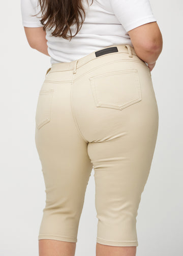 Skinnycapris för kvinnor i beige jeanstyg, färgen Gazelles. Närbild bakifrån på en plus size-modell, med fokus på fickor och sömmar.