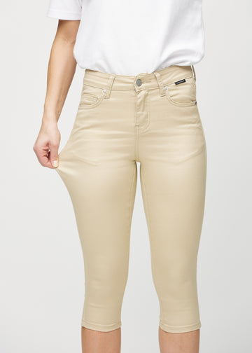 Skinnycapris för kvinnor i beige jeanstyg, färgen Gazelles. En modell drar i tyget för att visa flexibiliteten.