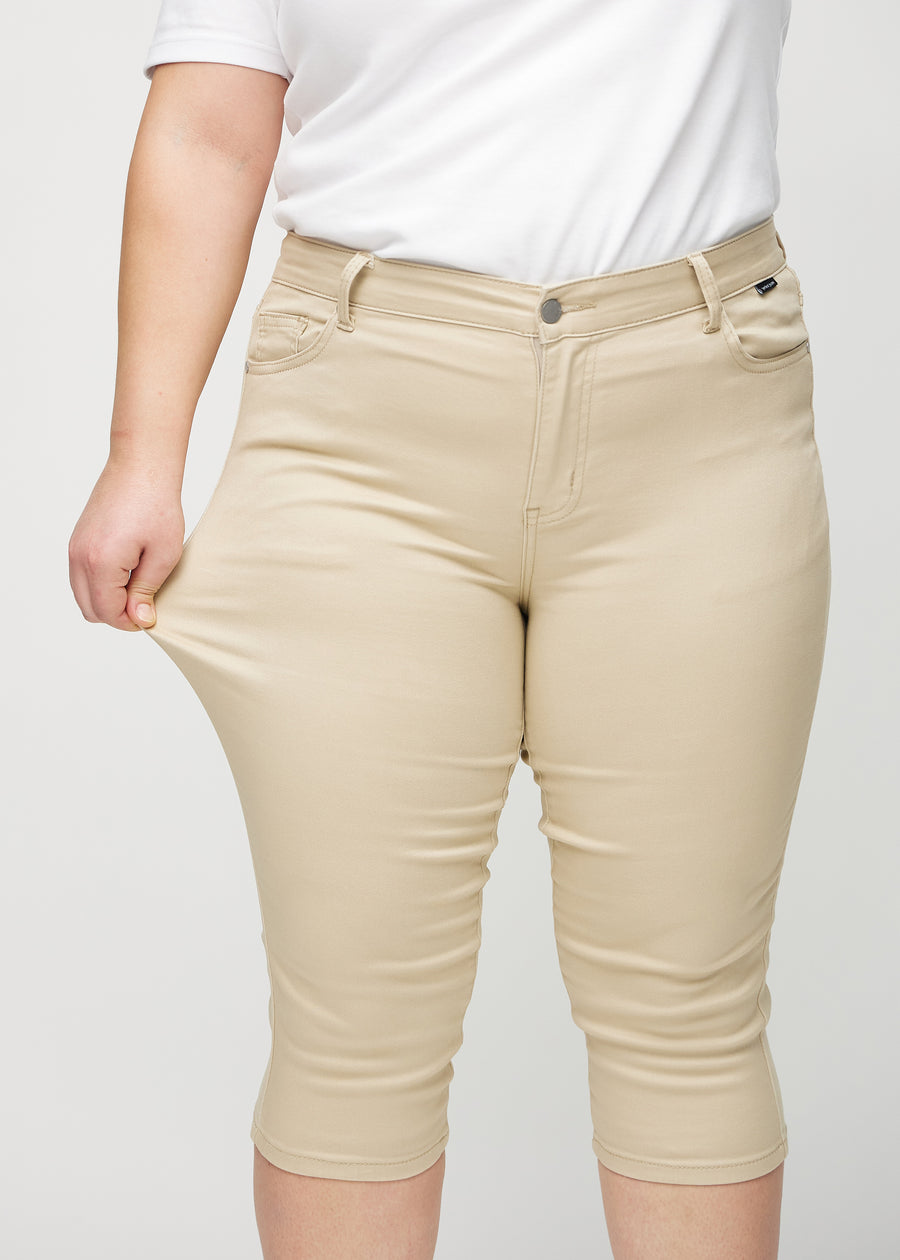 Skinnycapris för kvinnor i beige jeanstyg, färgen Gazelles. En plus size-modell drar i tyget för att visa flexibiliteten.