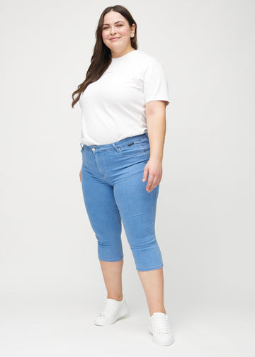 Skinnycapris för kvinnor i blått jeanstyg, färgen Geraniums. Helbild av en plus size-modell som bär capris.