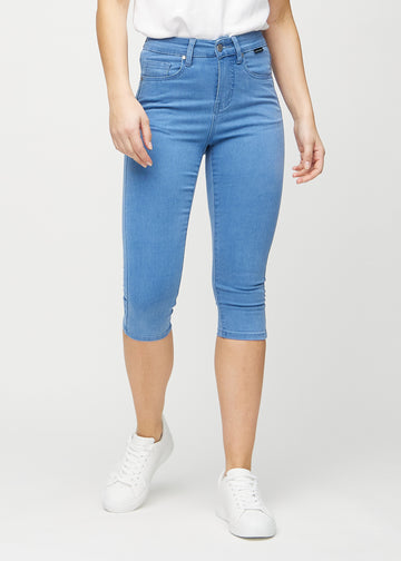 Skinnycapris för kvinnor i blått jeanstyg, färgen Geraniums. Framifrån på en modell, med åtsittande ben till strax under knät.
