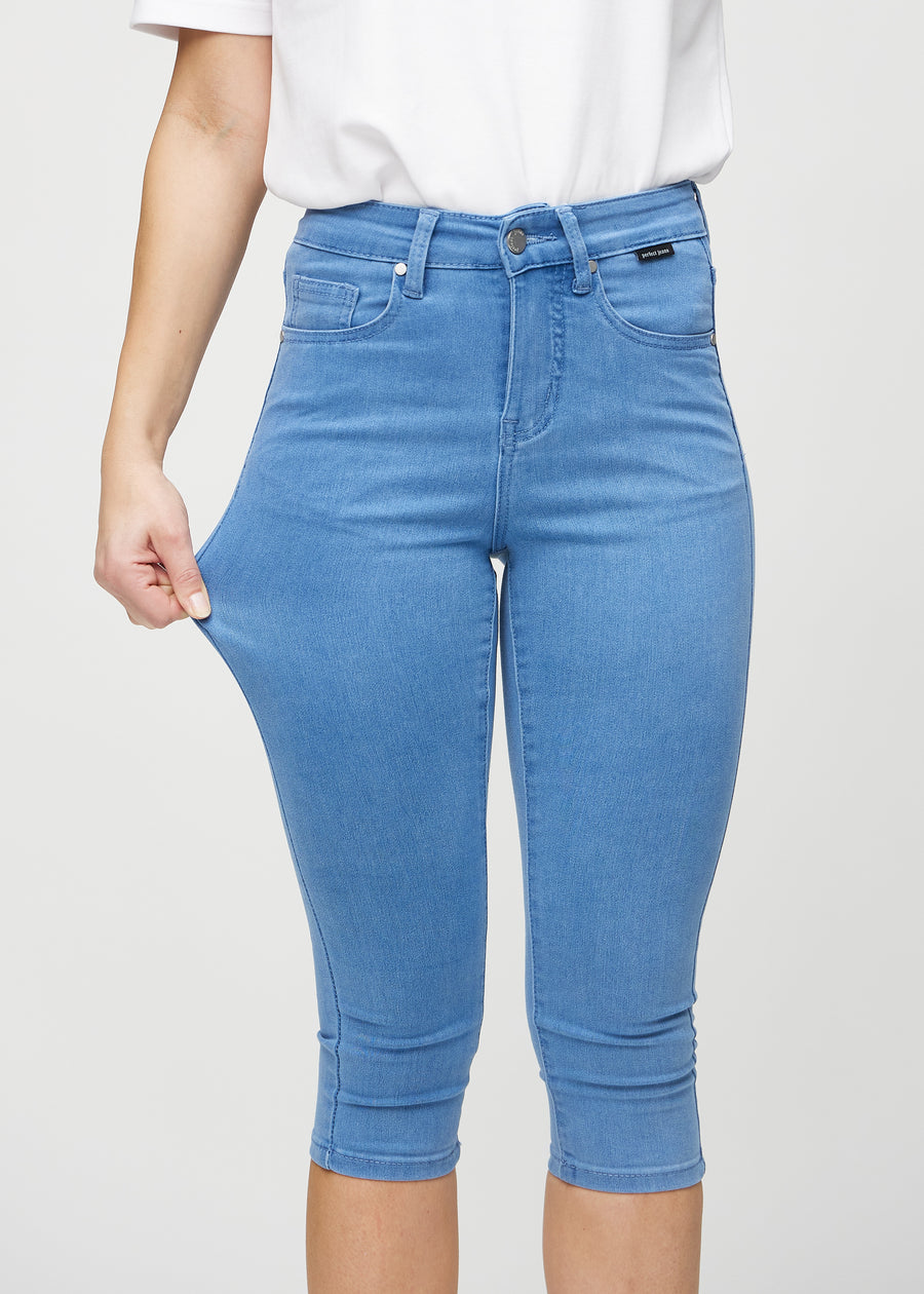 Skinnycapris för kvinnor i blått jeanstyg, färgen Geraniums. En modell drar i tyget för att visa flexibiliteten.
