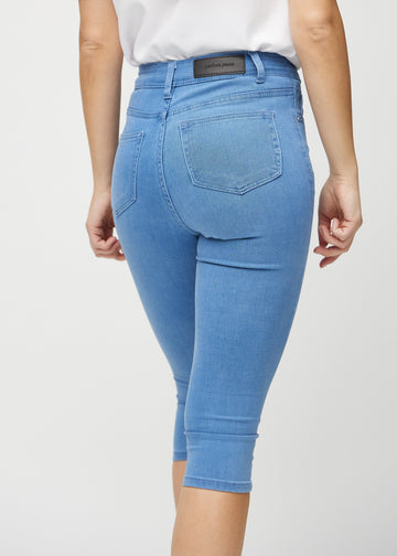 Skinnycapris för kvinnor i blått jeanstyg, färgen Geraniums. Närbild bakifrån på en modell, med fokus på fickor och sömmar.