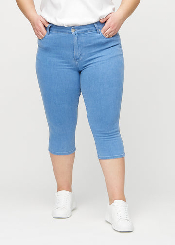 Skinnycapris för kvinnor i blått jeanstyg, färgen Geraniums. Framifrån på en plus size-modell, med åtsittande ben till strax under knät.