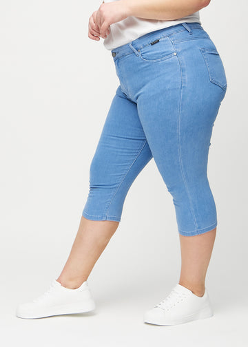 Skinnycapris för kvinnor i blått jeanstyg, färgen Geraniums. Från sidan på en plus size-modell, med åtsittande passform.