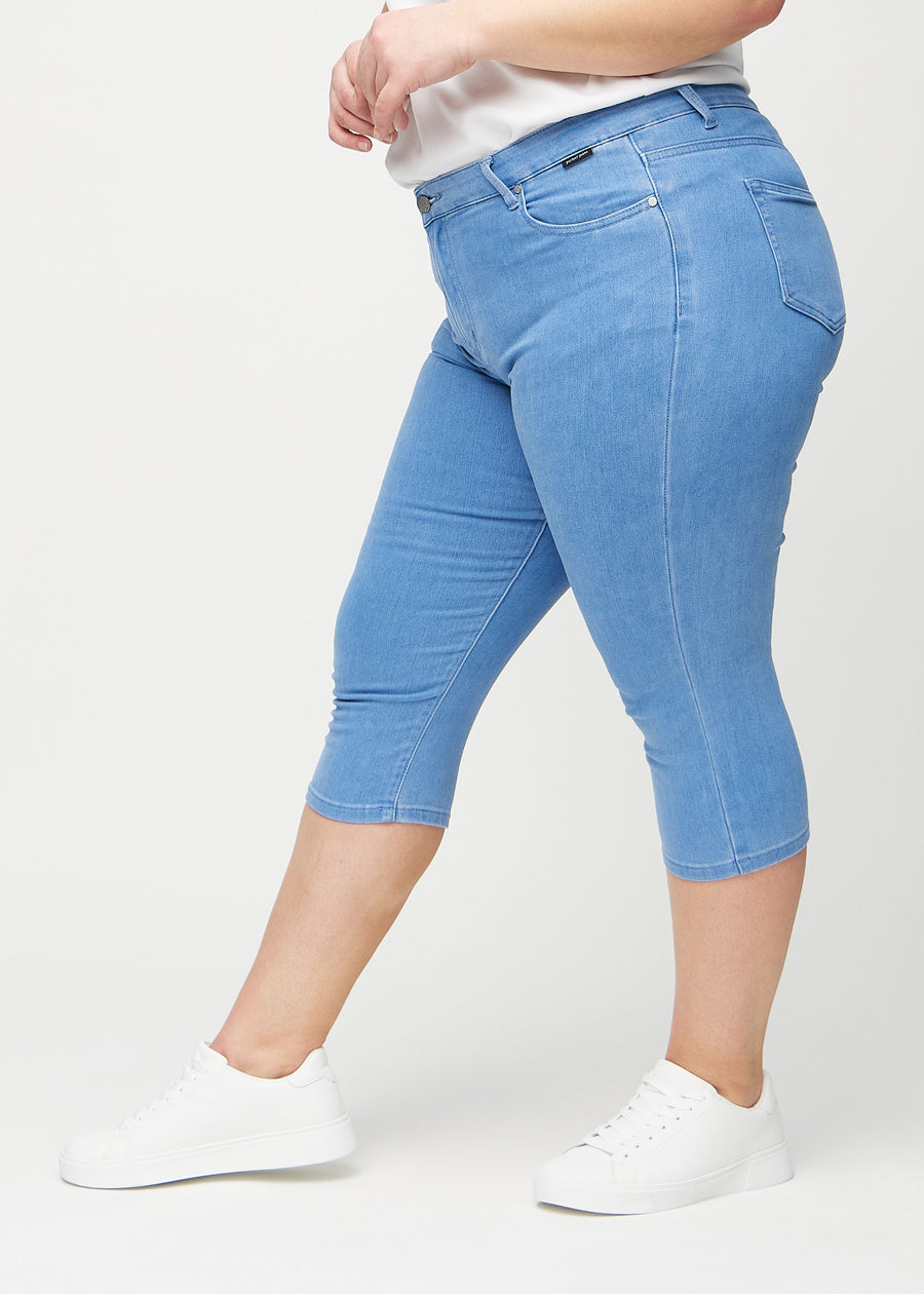 Skinnycapris för kvinnor i blått jeanstyg, färgen Geraniums. Från sidan på en plus size-modell, med åtsittande passform.