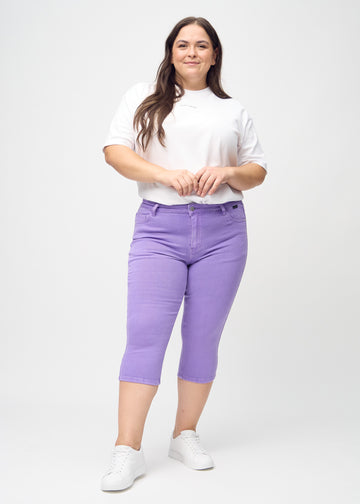 Skinnycapris för kvinnor i pastellila jeanstyg, färgen Lavenders. Helbild av en plus size-modell som bär capris.