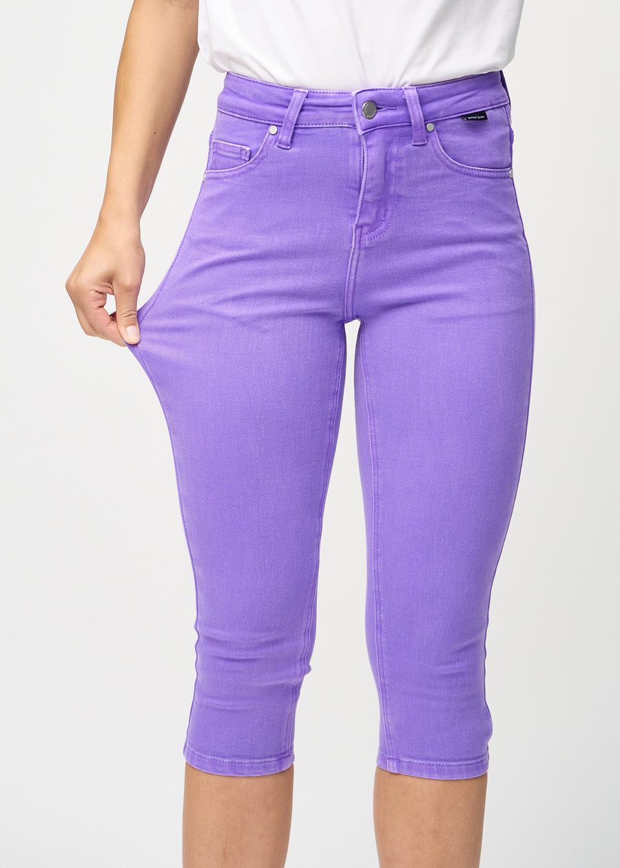 Skinnycapris för kvinnor i pastellila jeanstyg, färgen Lavenders. En modell drar i tyget för att visa flexibiliteten.
