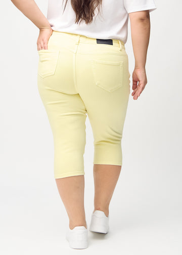 Skinnycapris för kvinnor i pastellgult jeanstyg, färgen Lemonades. Bakifrån på en plus size-modell, med fokus på passform och bakfickor.