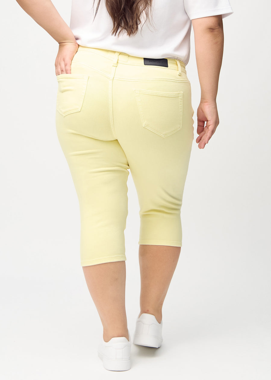 Skinnycapris för kvinnor i pastellgult jeanstyg, färgen Lemonades. Bakifrån på en plus size-modell, med fokus på passform och bakfickor.