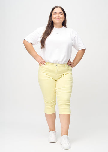 Skinnycapris för kvinnor i pastellgult jeanstyg, färgen Lemonades. Helbild av en plus size-modell som bär capris.