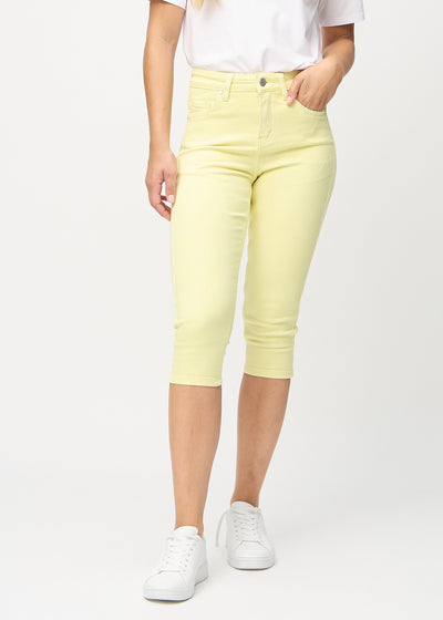Skinnycapris för kvinnor i pastellgult jeanstyg, färgen Lemonades. Framifrån på en modell, med åtsittande ben till strax under knät.
