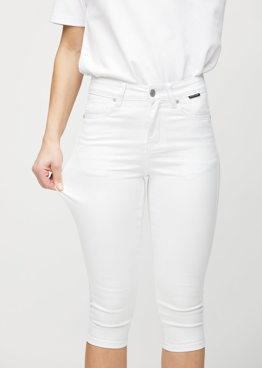 Skinnycapris för kvinnor i vitt jeanstyg, färgen Marguerites. En modell drar i tyget för att visa flexibiliteten.