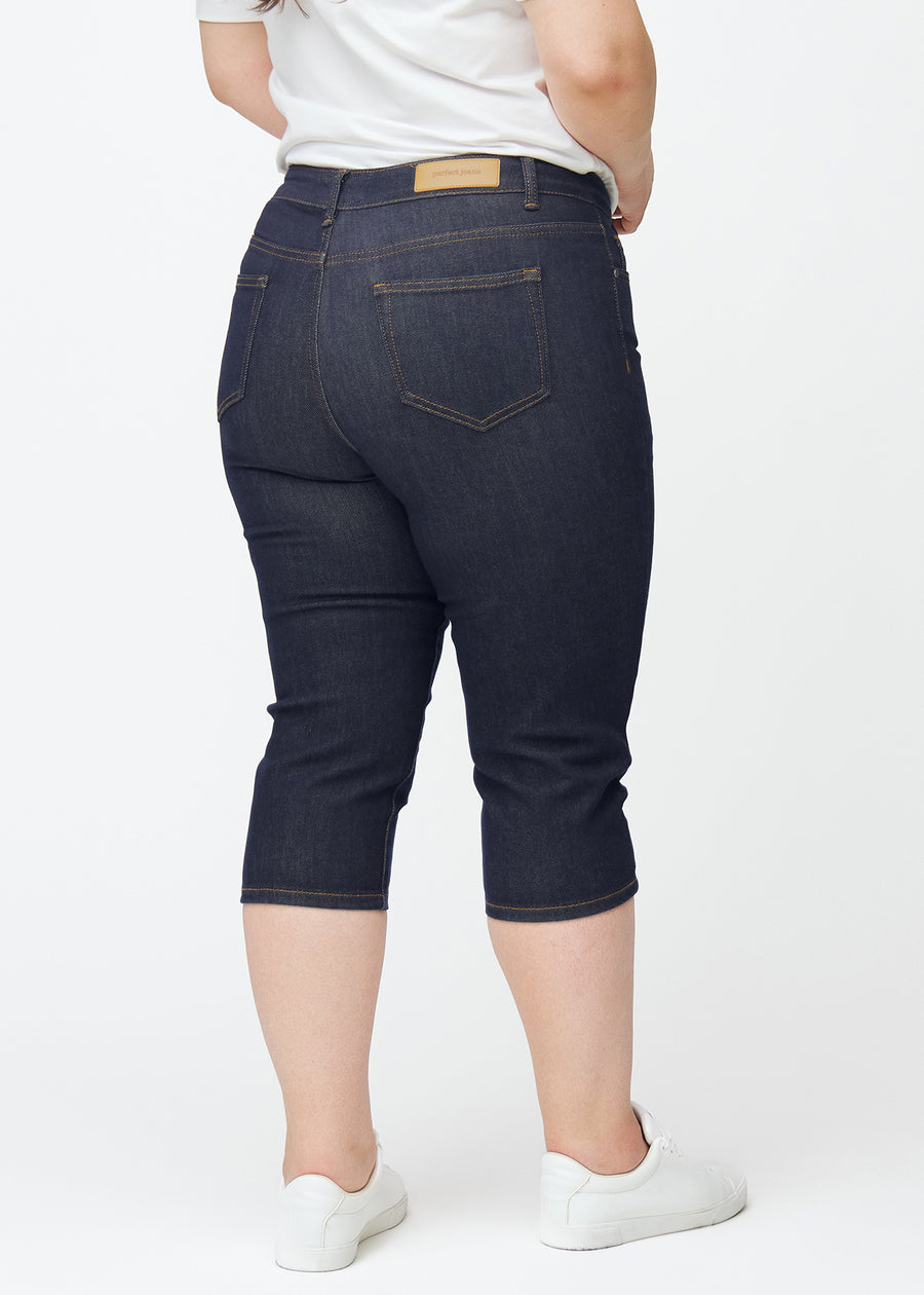 Mörkblå denim capris för dam i färgen Midnights sett bakifrån på plus-size modell.