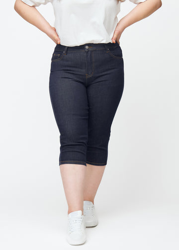 Mörkblå denim capris för dam i färgen Midnights med skinny passform sett framifrån på plus-size modell.