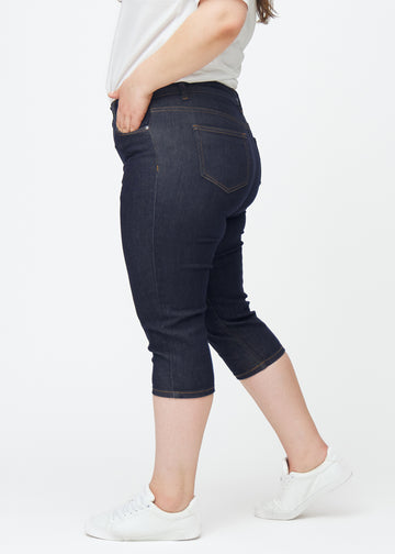 Mörkblå denim capris för dam i färgen Midnights med skinny passform sett från sidan på plus-size modell.