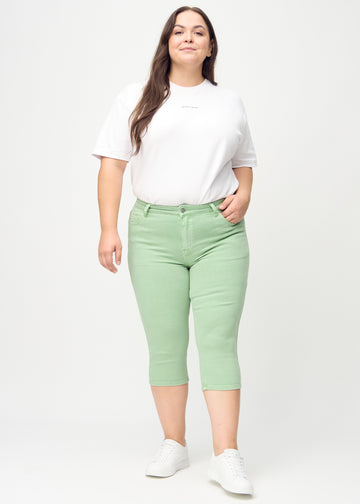 Skinnycapris för kvinnor i pastellgrönt jeanstyg, färgen Mints. Helbild av en plus size-modell som bär capris.