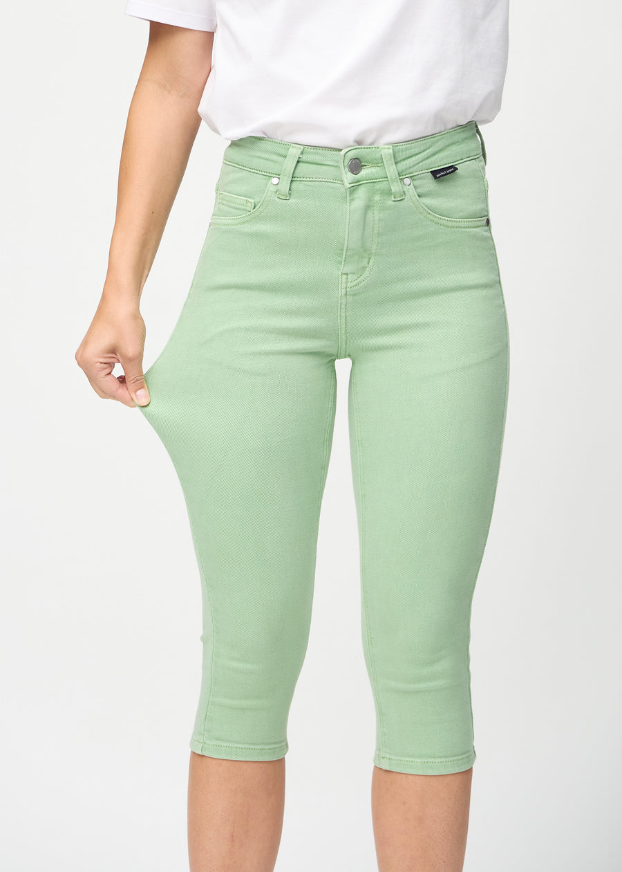 Skinnycapris för kvinnor i pastellgrönt jeanstyg, färgen Mints. En modell drar i tyget för att visa flexibiliteten.