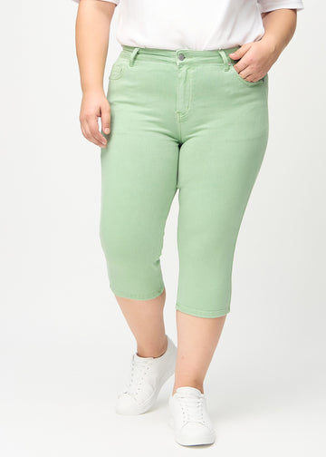 Skinnycapris för kvinnor i pastellgrönt jeanstyg, färgen Mints. Framifrån på en plus size-modell, med åtsittande ben till strax under knät.