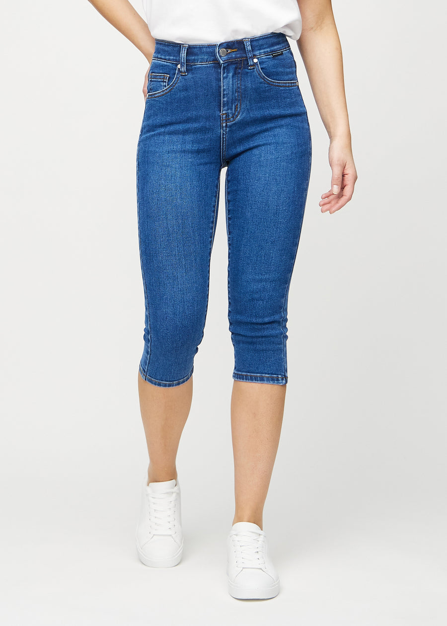 Skinnycapris för kvinnor i mörkblå denim, färgen Oceans. Framifrån på en modell, med åtsittande ben till strax under knät.