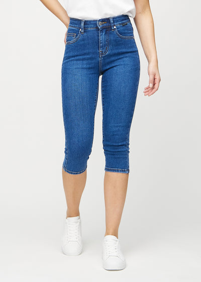 Skinnycapris för kvinnor i mörkblå denim, färgen Oceans. Framifrån på en modell, med åtsittande ben till strax under knät.