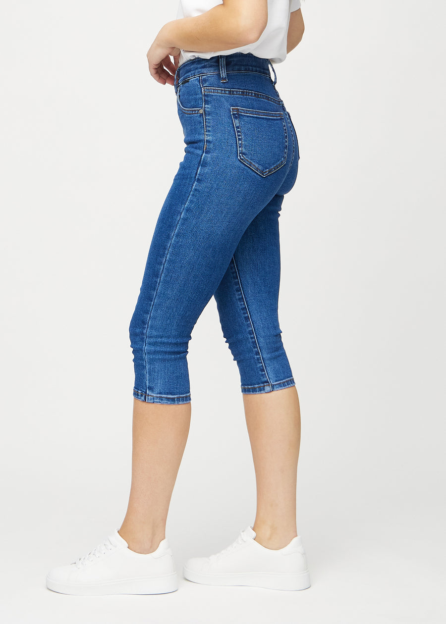 Skinnycapris för kvinnor i mörkblå denim, färgen Oceans. Från sidan på en modell, med åtsittande passform.