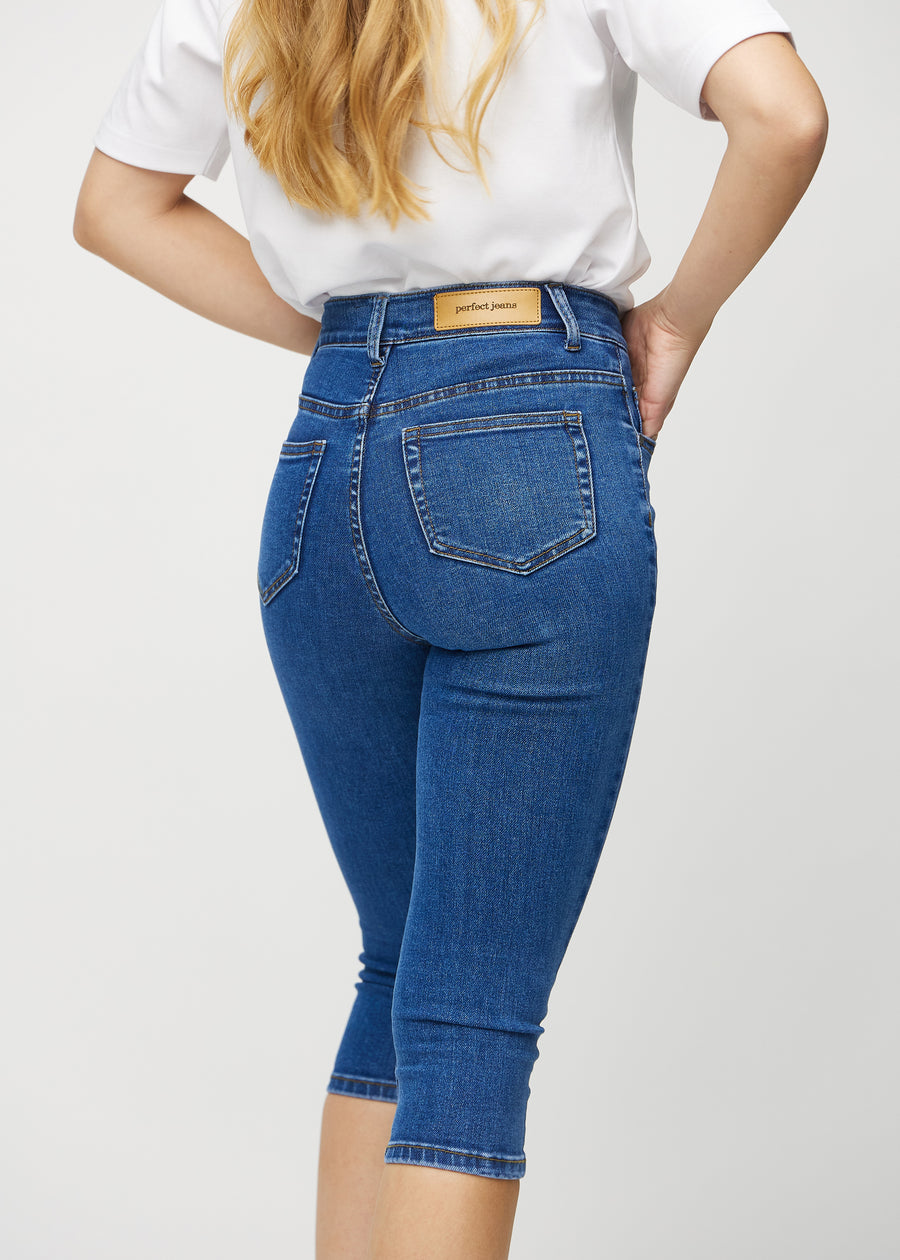 Skinnycapris för kvinnor i mörkblå denim, färgen Oceans. Närbild bakifrån på en modell, med fokus på fickor och sömmar.