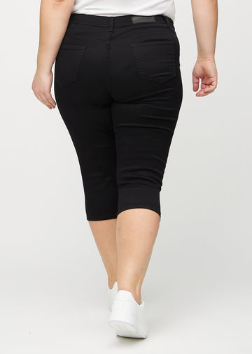 Svarta skinny capris sedda bakifrån på en plus-size-modell, så att hela produkten syns.
