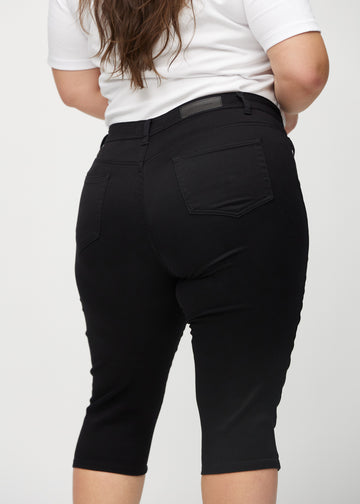 Svarta skinny capris sedda bakifrån i närbild på en plus-size-modell för att visa detaljer.