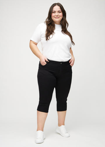 Helbild av en plus-size-modell i svarta skinny capris.