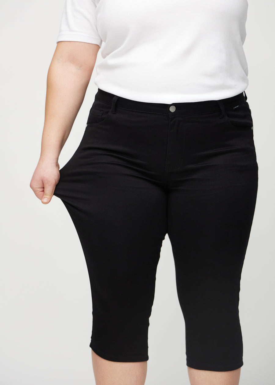 Plus-size-modellen drar ut caprisen vid låret för att visa stretch.