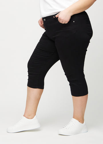 Svarta skinny capris sedda från sidan på en plus-size-modell.