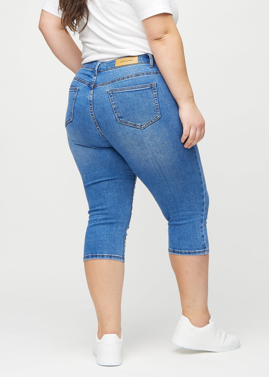 Denim skinny capris sedd bakifrån på en plus size-modell, så att man kan se hela produkten.
