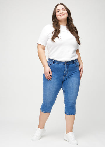 Helbild av en plus size-modell i denim skinny capris.