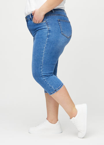 Denim skinny capris sedd från sidan på en plus size-modell.