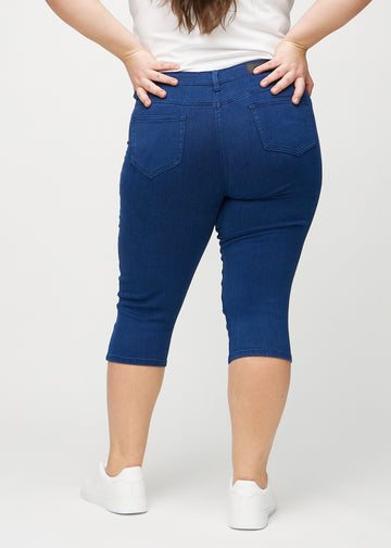 Skinnycapris för kvinnor i mörkblått jeanstyg, färgen Royals. Bakifrån på en plus size-modell, med fokus på passform och bakfickor.